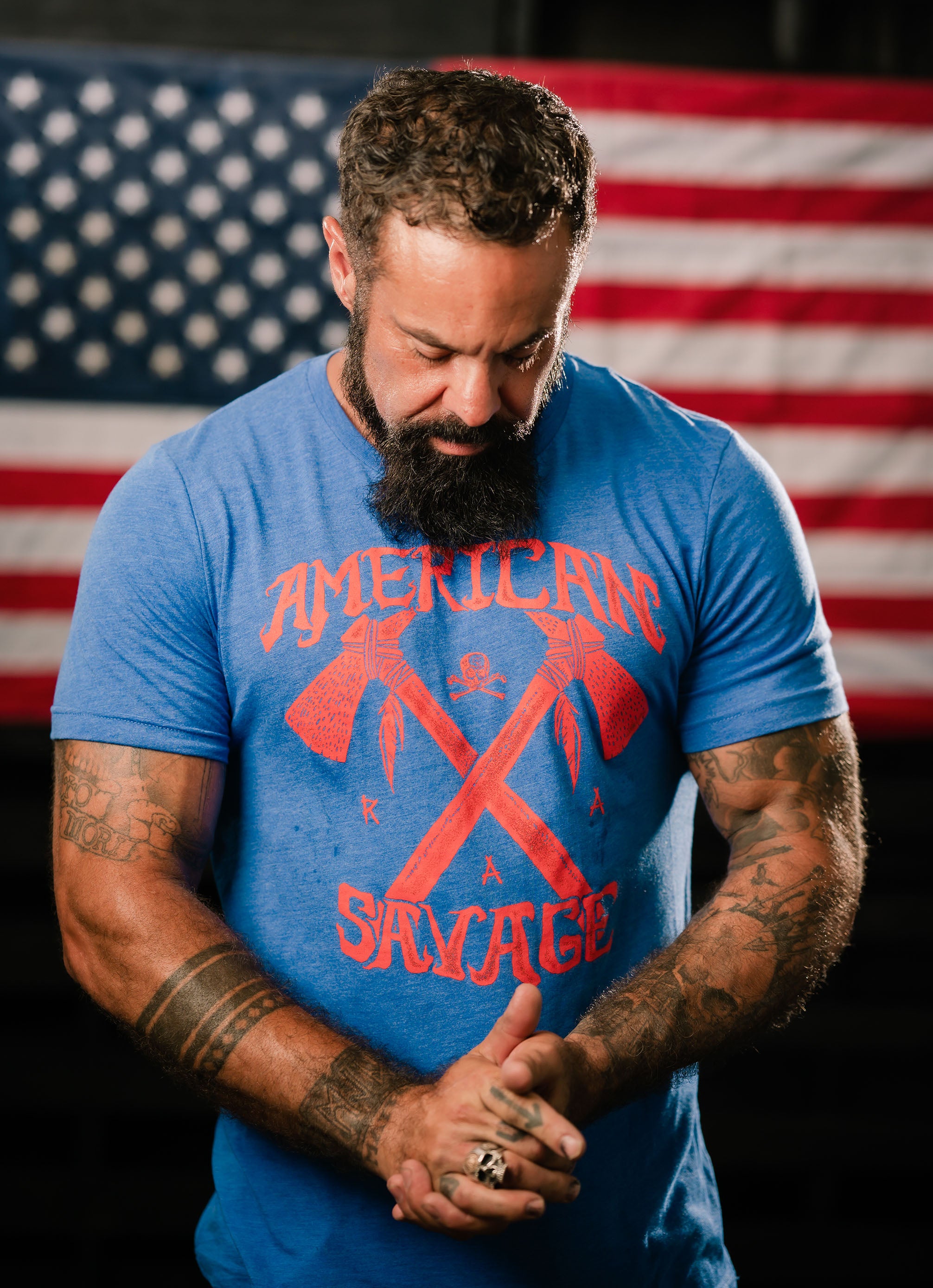 man wearing Rogue American savage shirt in front of American flag